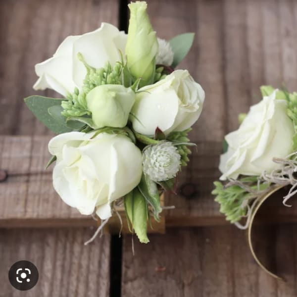 White rose wrist corsages with green accents on ribbon bands