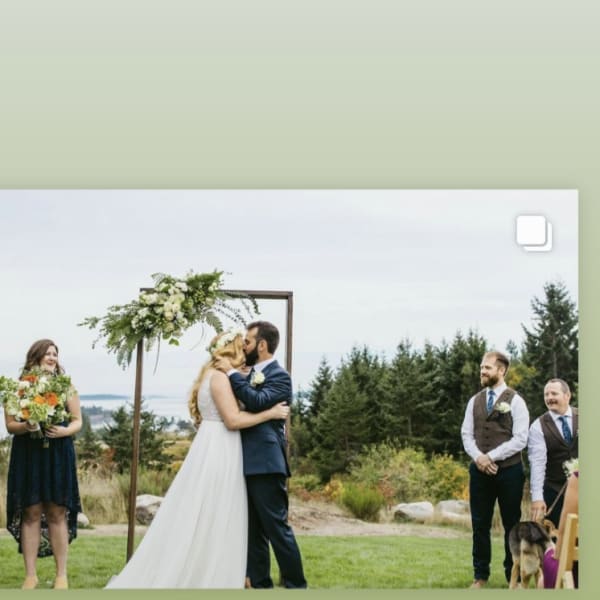 Bride and groom kissing under a floral wedding arch outdoors