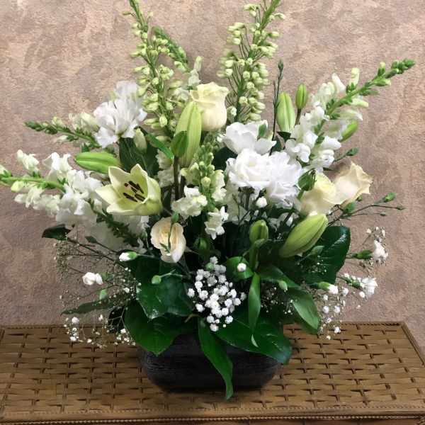 White floral arrangement in a black bowl vase with tall stems
