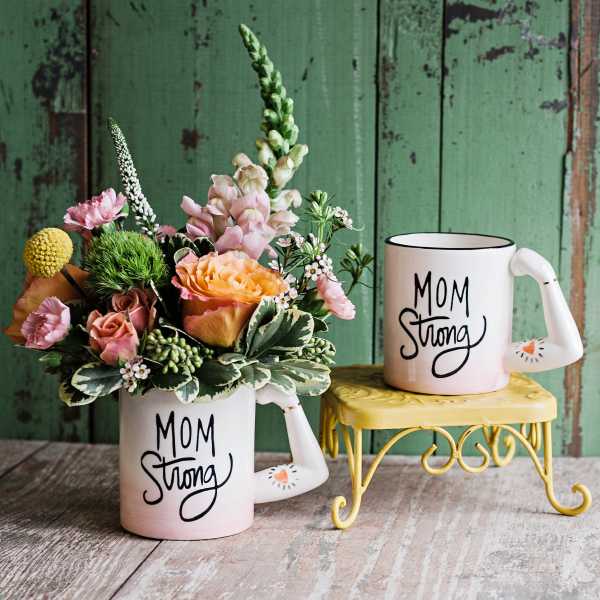 Floral arrangement in a mug with a matching "Mom Strong" mug beside it