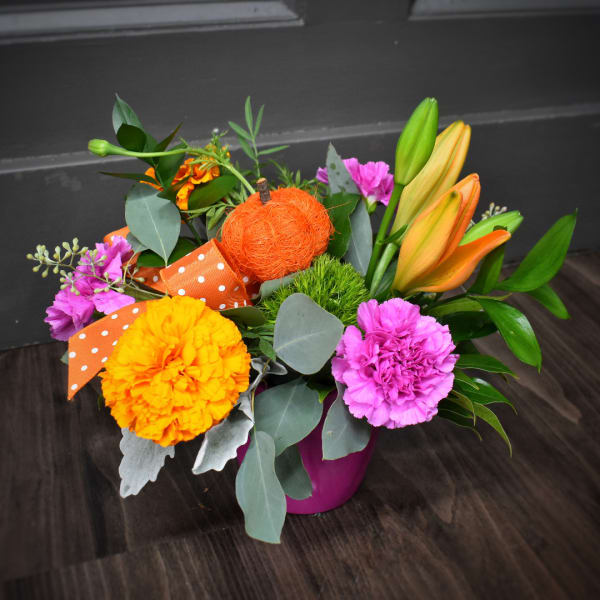 Colorful flower arrangement in a pink vase with lilies and carnations