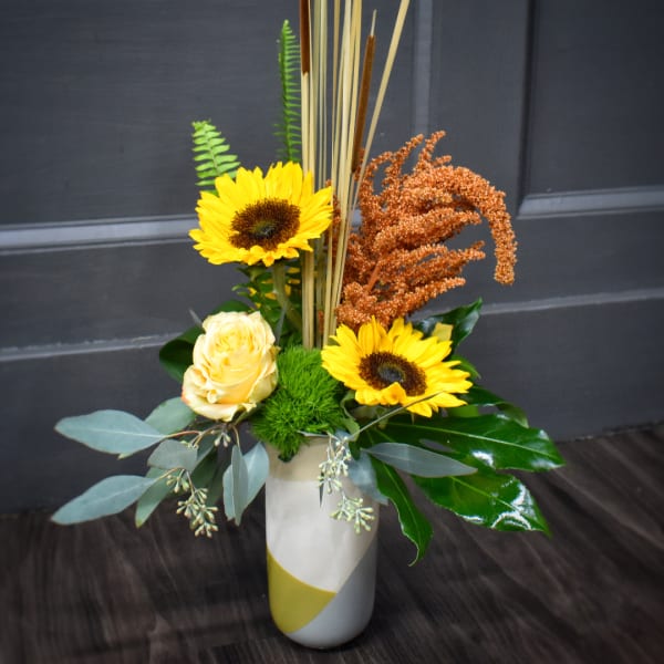 Sunflower and rose arrangement in a tall white vase