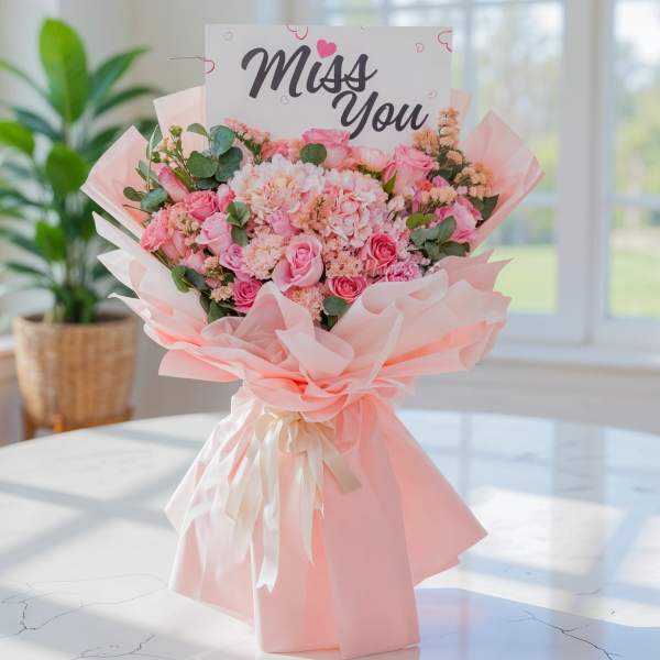 Pink bouquet with roses and hydrangeas, wrapped in pale pink paper with a "Miss You" card