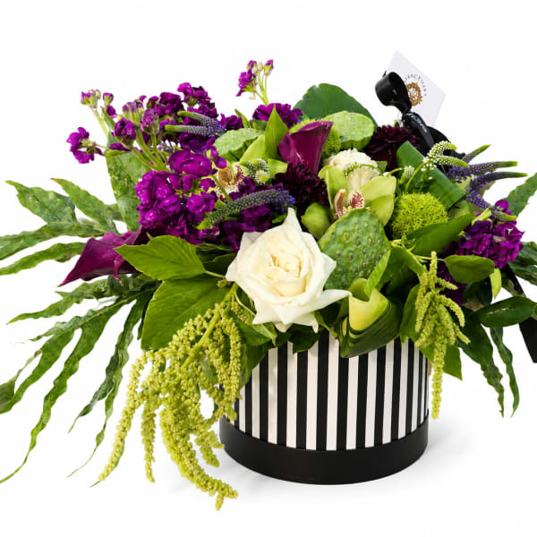 Purple and white floral arrangement in a striped round box