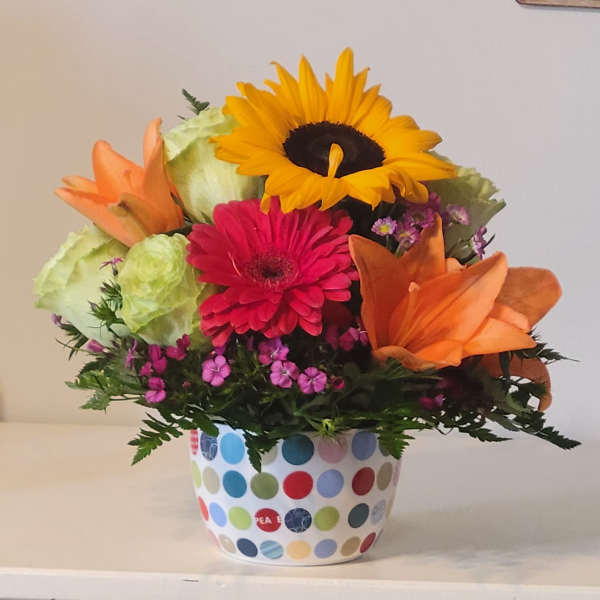 Mixed bouquet with a sunflower, gerbera daisy, lilies, and a polka-dot pot