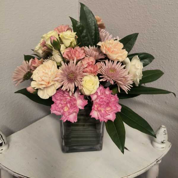 Pink and cream mixed bouquet in a square glass vase