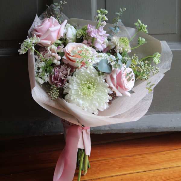 Bouquet of pink roses and white chrysanthemums wrapped in pale paper