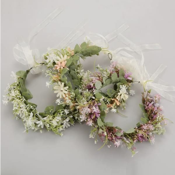 Two floral wreaths with white and pink blossoms tied with sheer ribbon
