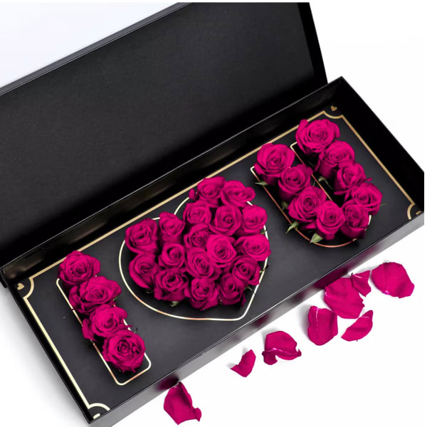Magenta roses arranged in a black gift box spelling "MOM"