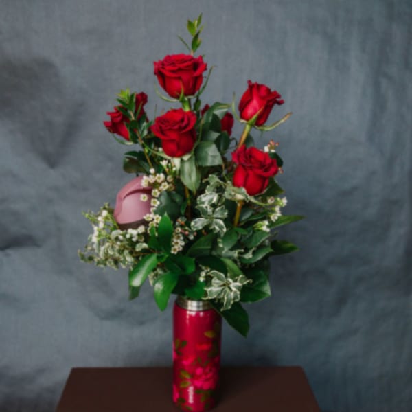 Red roses arranged in a red vase with white filler flowers
