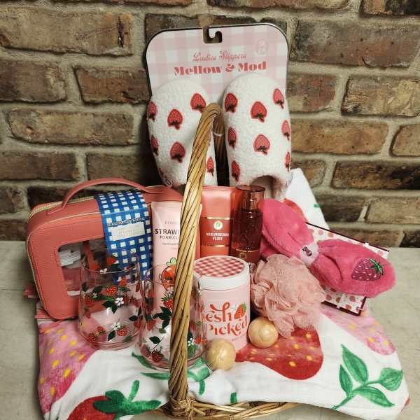 Gift basket with strawberry-themed slippers, socks, and bath items