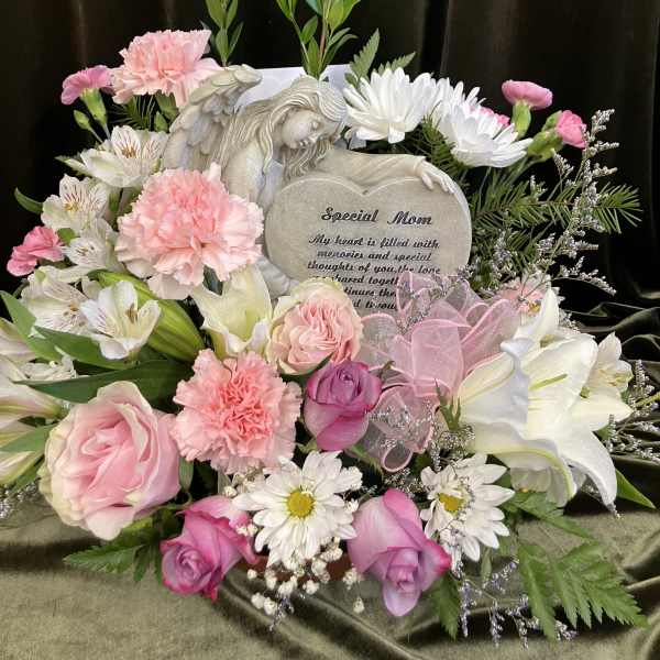 Pink and white floral arrangement with a memorial plaque and angel figurine