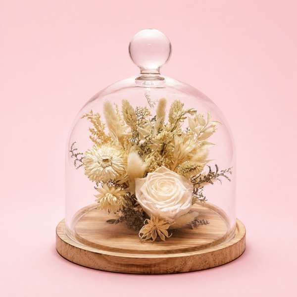 Dried floral arrangement under a glass dome on a wooden base