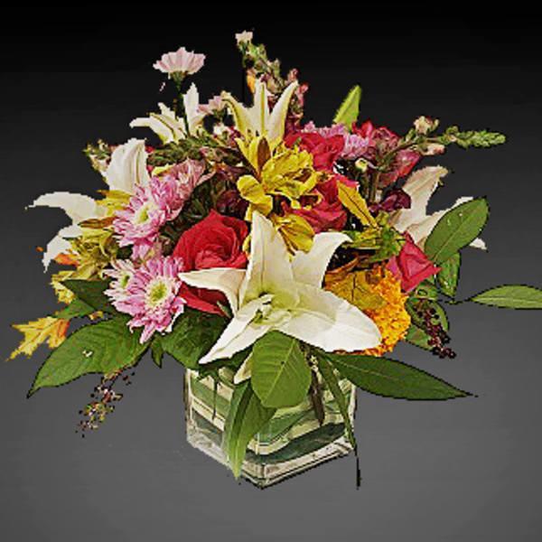 Mixed bouquet of lilies, roses, and daisies in a square glass vase
