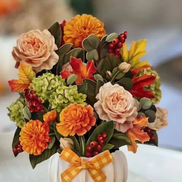 Fall floral arrangement in a white pumpkin container with an orange ribbon