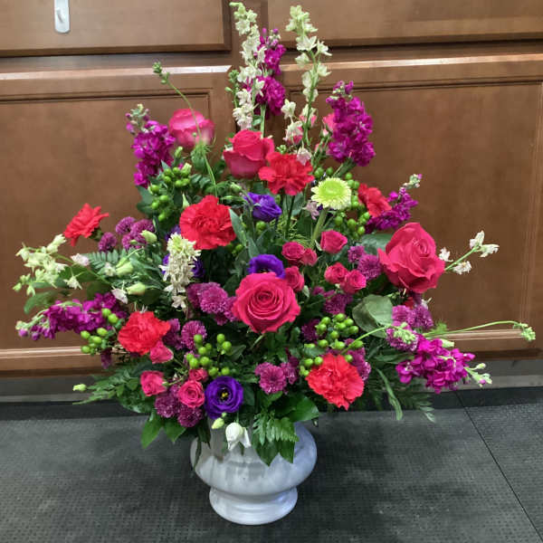 Large mixed floral arrangement in a white urn vase