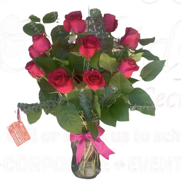 Bouquet of red roses in a glass vase with a pink ribbon