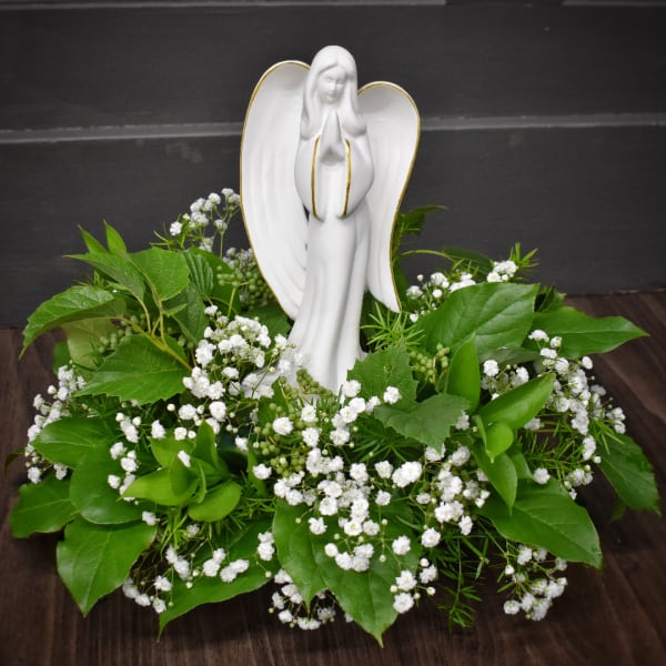 White angel figurine surrounded by baby's breath and green foliage
