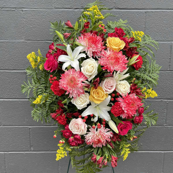 Standing floral spray with pink, white, and yellow blooms on an easel