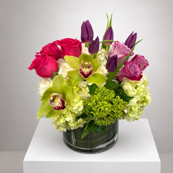 Pink roses and green orchids arranged in a glass vase