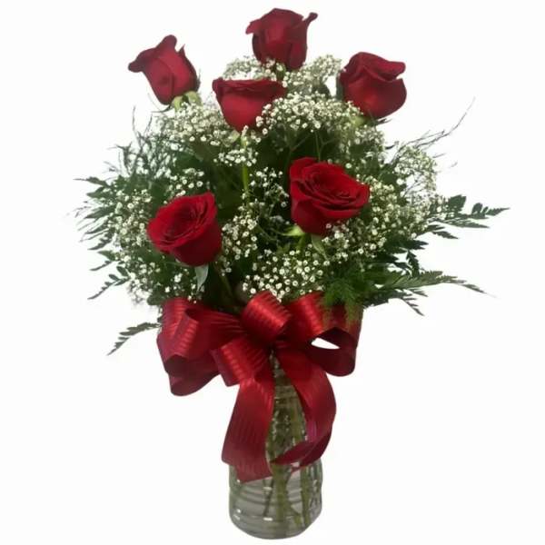 Red roses in a glass vase with baby's breath and a red ribbon