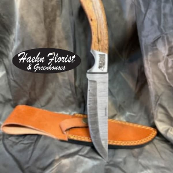 Hunting knife with a leather sheath on dark fabric