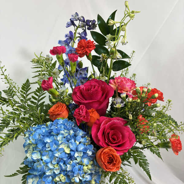 Colorful mixed bouquet in a clear glass vase with roses and hydrangea