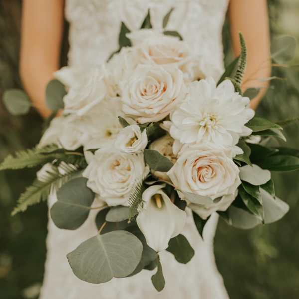 Bride holding a white bouquet of roses, dahlias, and calla lilies