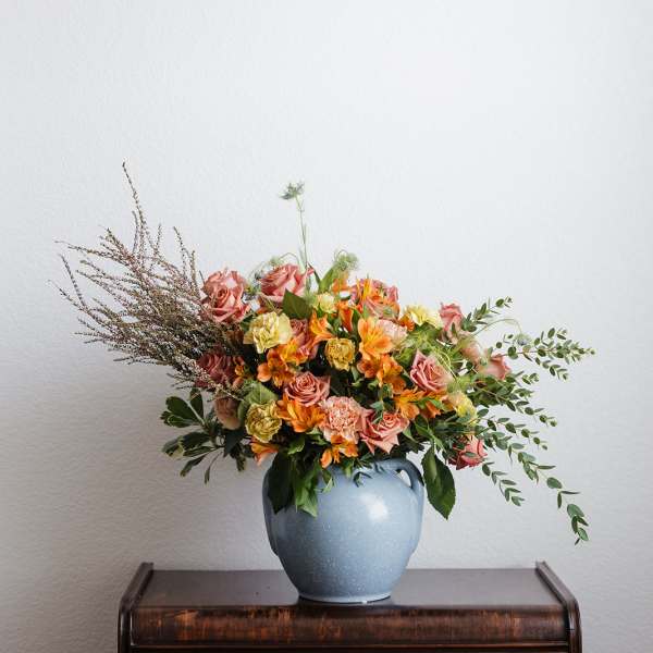 Mixed bouquet of pink and orange flowers in a blue vase