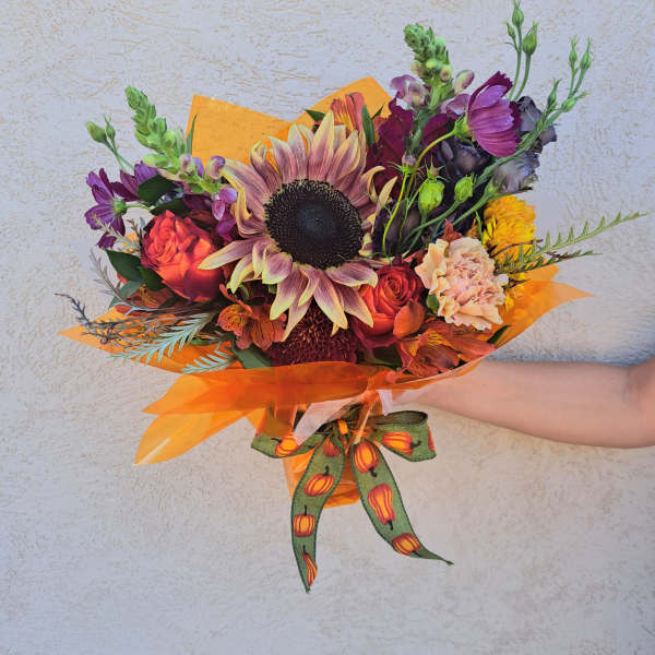 Mixed bouquet with a large sunflower and orange-purple blooms wrapped in orange paper