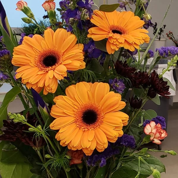 Bouquet of orange gerbera daisies with purple accent flowers