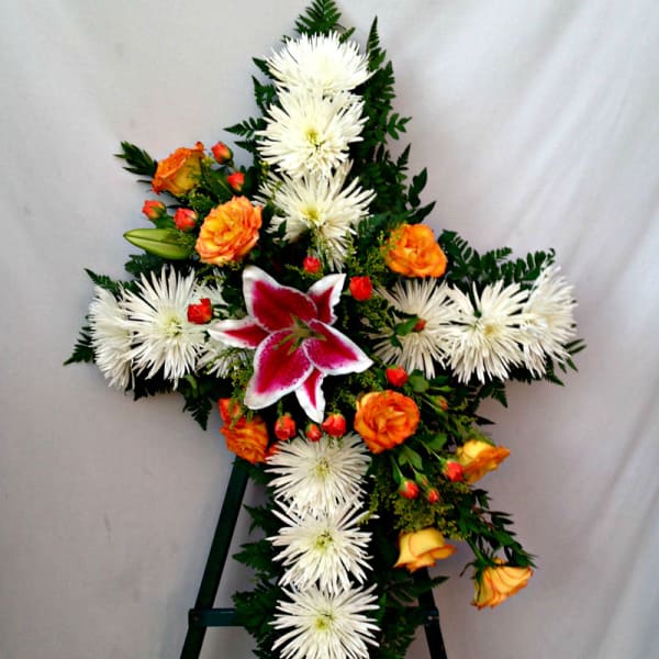 Cross-shaped floral spray with white spider mums, orange roses, and a pink lily