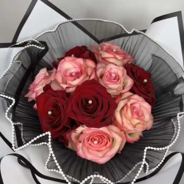 Bouquet of red and pink roses wrapped in black paper