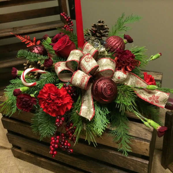 Christmas centerpiece with red flowers, pinecones, and a tall red candle