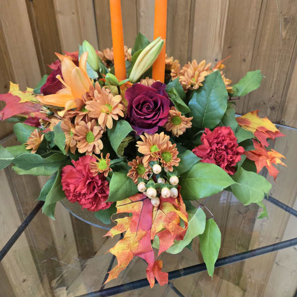 Autumn floral centerpiece with orange candles in a low glass bowl