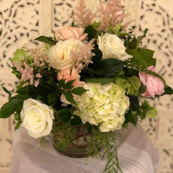 Bouquet of white and blush roses with pale green hydrangea in a vase
