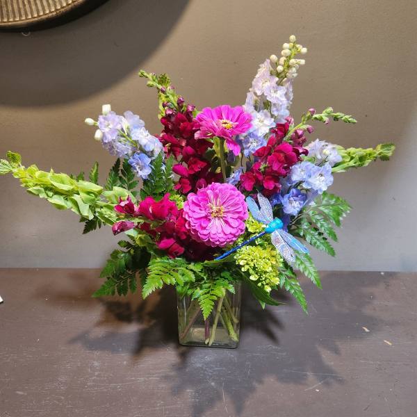 Colorful mixed flower arrangement in a square glass vase