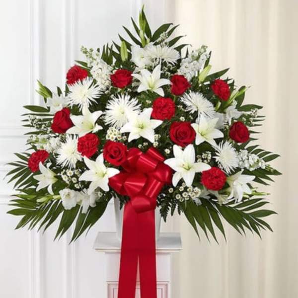 Standing floral spray with red and white flowers and a red ribbon