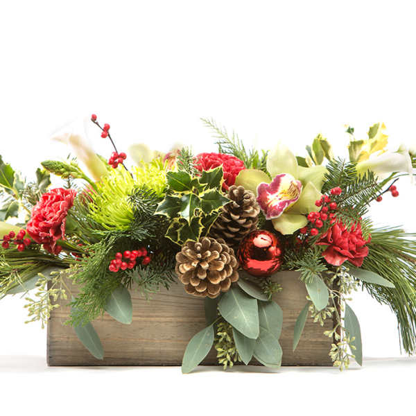 Holiday floral arrangement in a wooden box with pinecones and red blooms