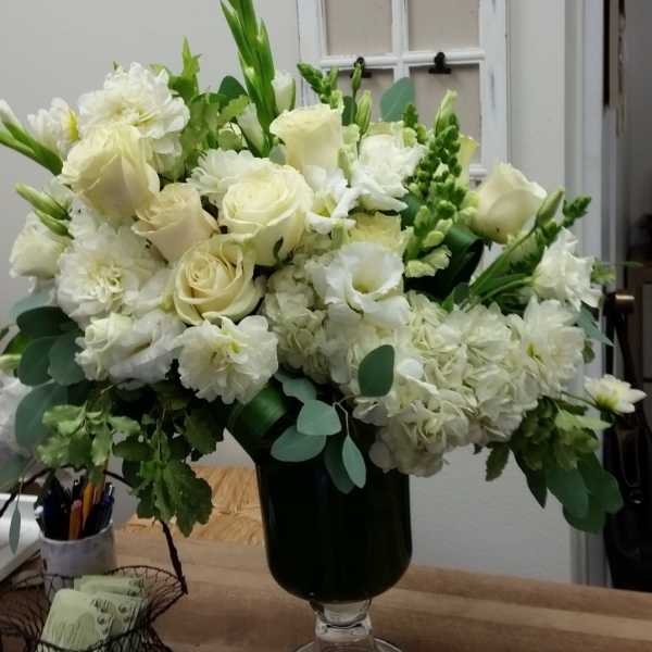 White roses and mixed white flowers in a dark glass vase