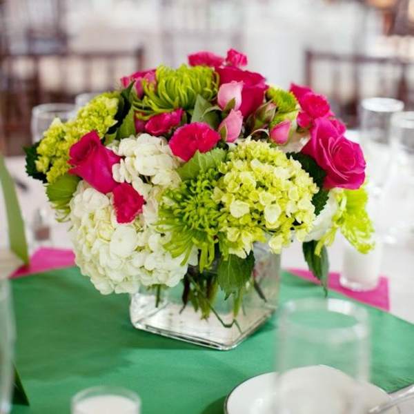 Pink and green floral centerpiece in a square glass vase