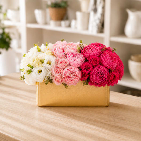 Pink and white flower arrangement in a gold rectangular vase