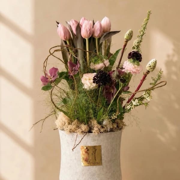 Pink tulips and mixed flowers arranged in a white vase