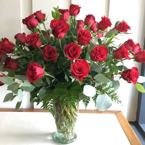 A large bouquet of red roses in a clear glass vase