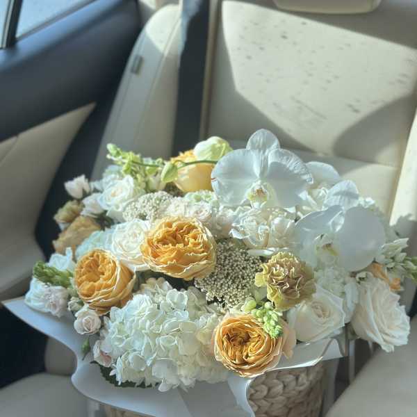Bouquet of white and peach flowers in a woven basket