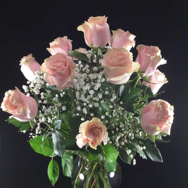 Pink roses arranged in a clear glass vase with white baby's breath