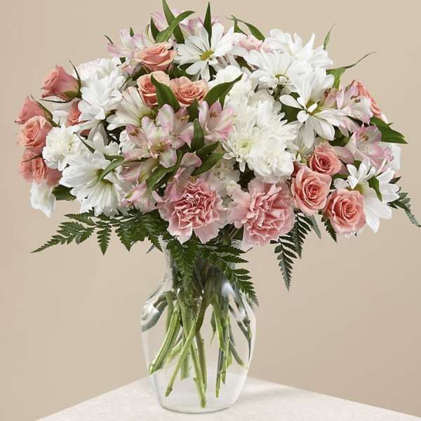 Pink roses and white daisies arranged in a clear glass vase