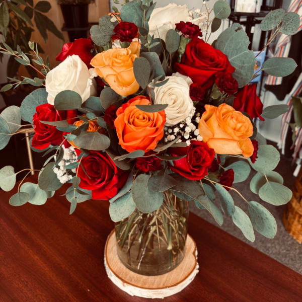 Bouquet of red, orange, and white roses in a glass vase