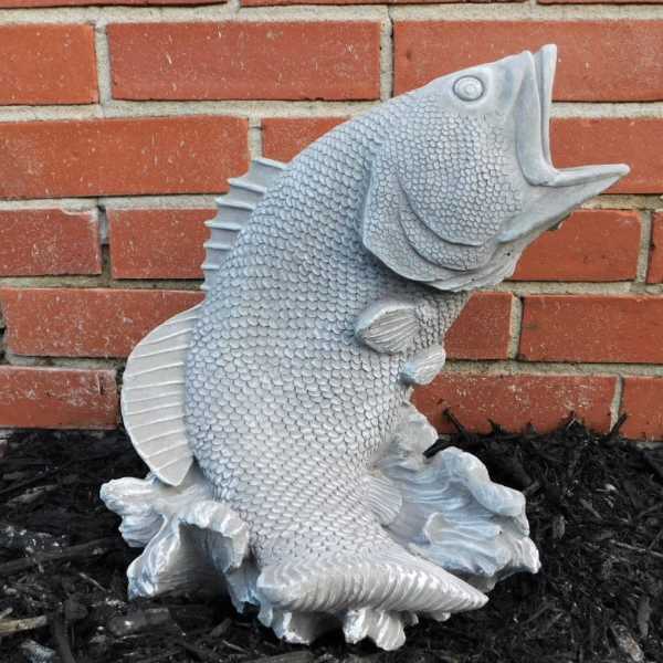 Silver fish sculpture against a brick wall