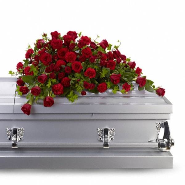 Red rose and carnation arrangement on a gray casket